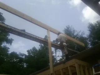 Carpenter setting a ridge beam over a new addition frame — Ice Dam Removal by Roofing Brothers in Cross