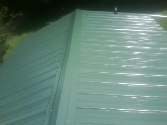 New green metal panels meeting at the ridge of a roof — Flat Roof Repair work by our crew in Cross
