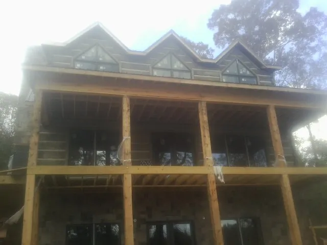 Dormers and porch framing on a large log home under construction — Roof Coating work by our crew in Cross
