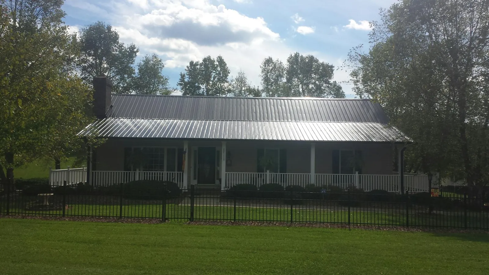 Gray metal roof on a brick ranch with a full width front porch — Gutter Guard Installation work by our crew in Cross