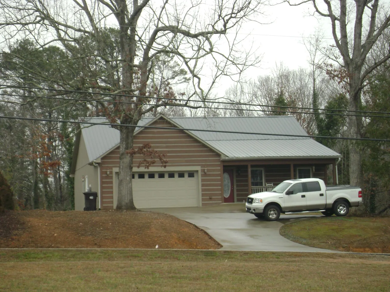 Gray metal roof on a log sided house with an attached two car garage in Cross